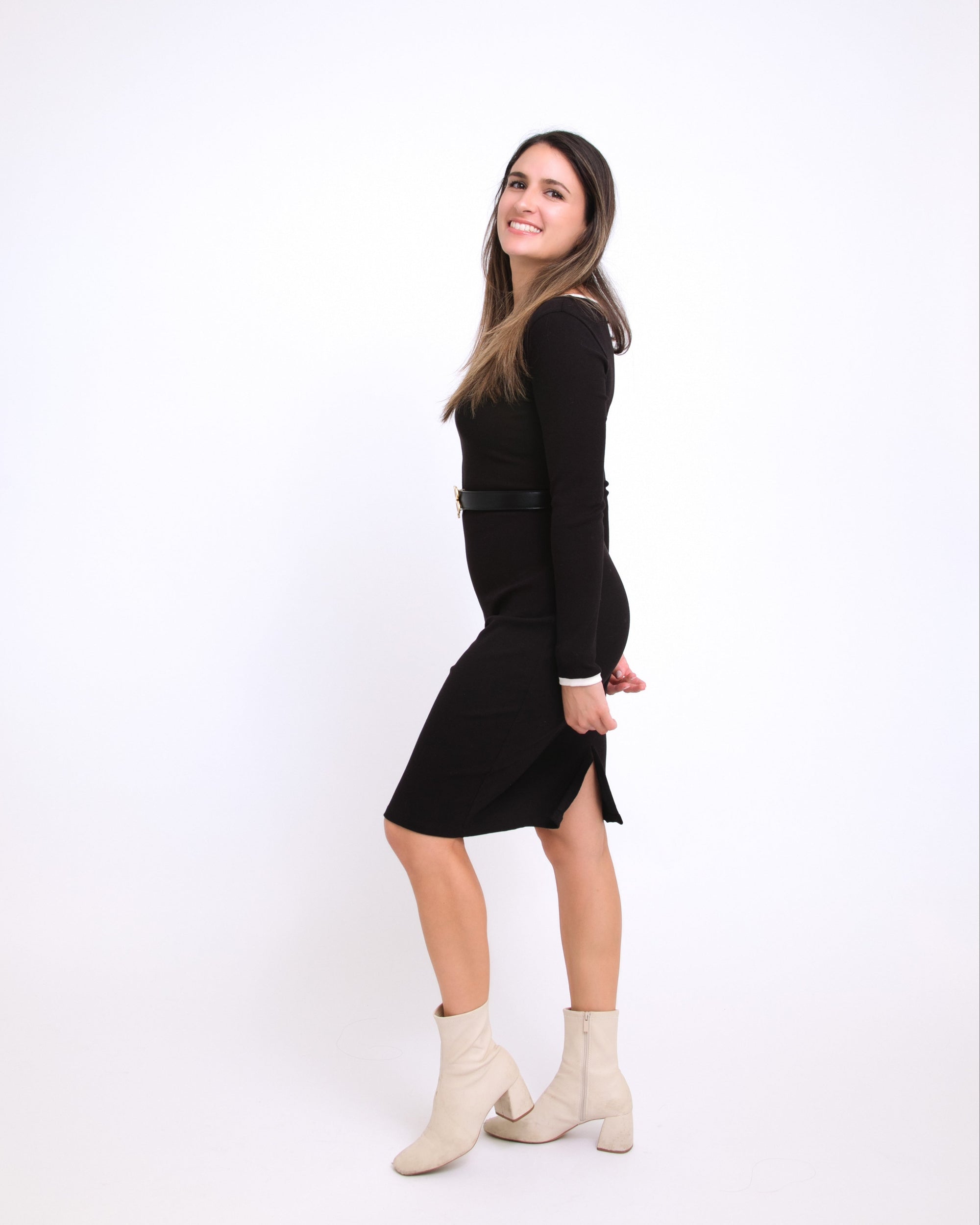 Woman wearing a black dress and white boots on a white background