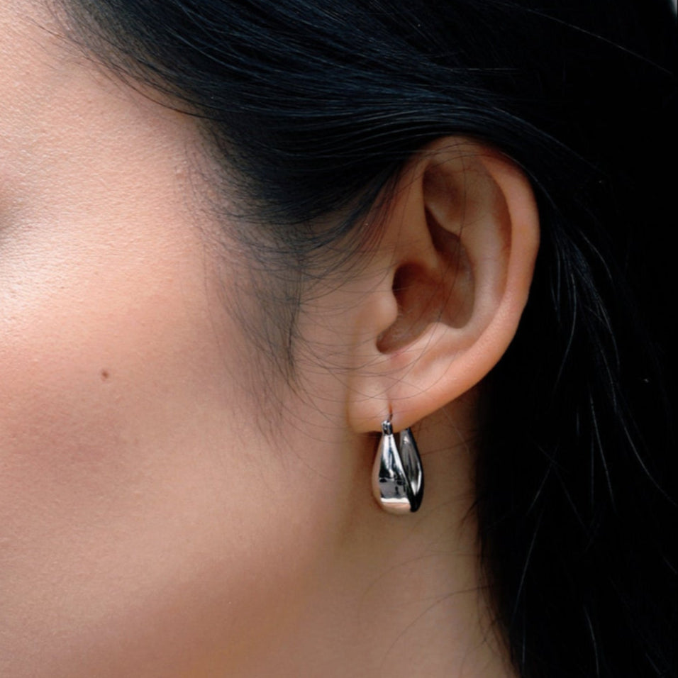Close-up of an ear wearing a silver earring with a blurred background