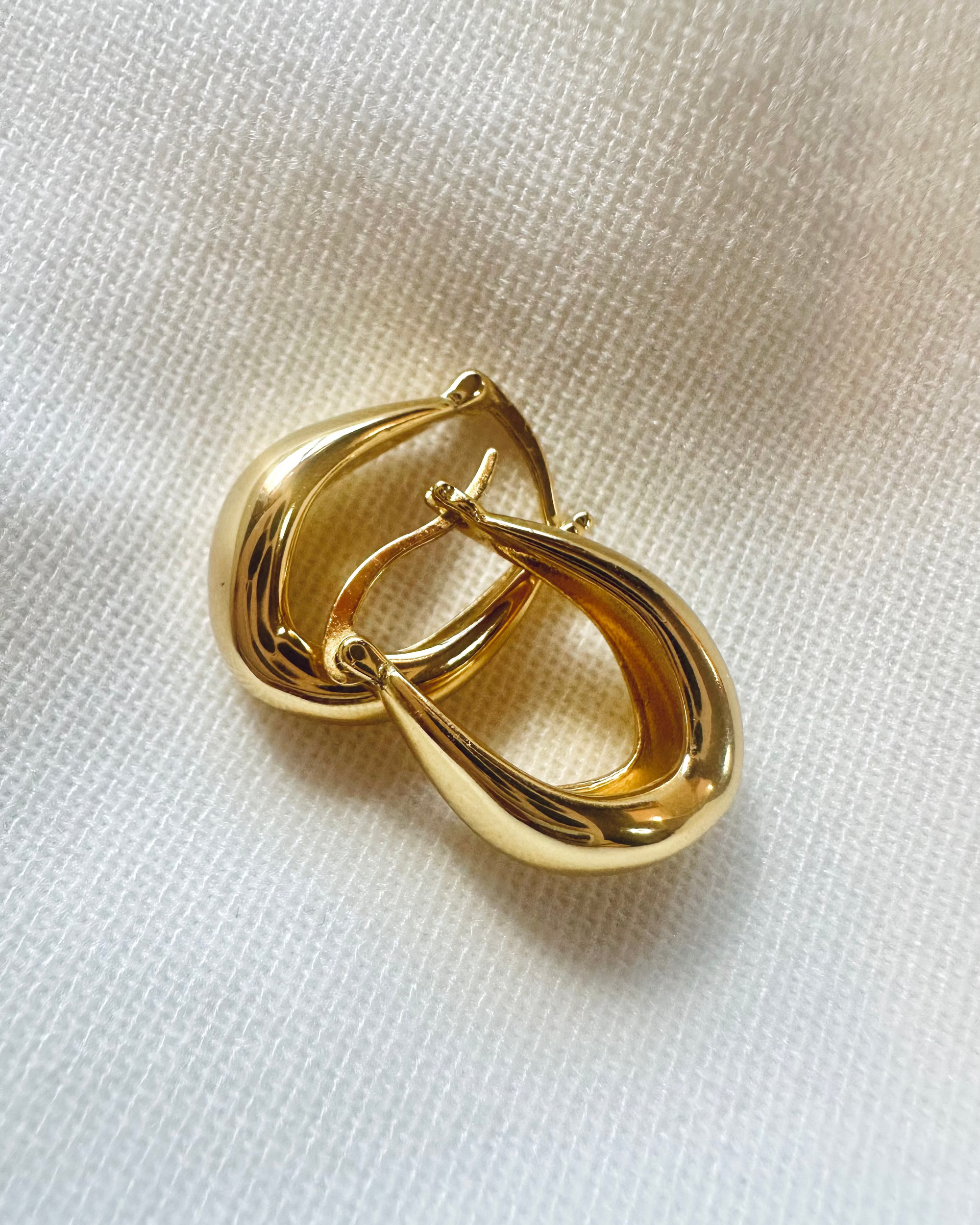 Gold earring on a white fabric background