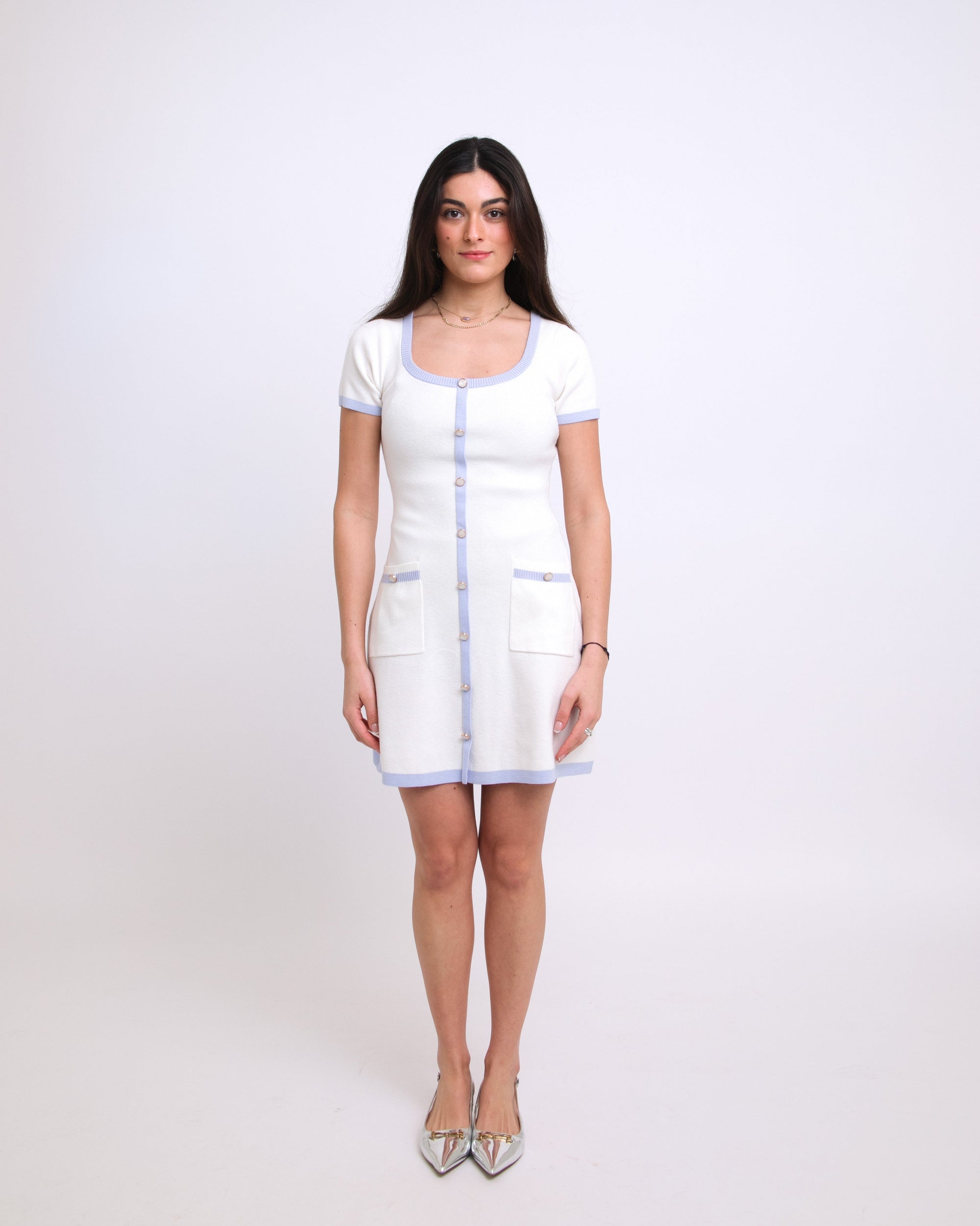 Woman wearing a white dress with a blue trim on a white background