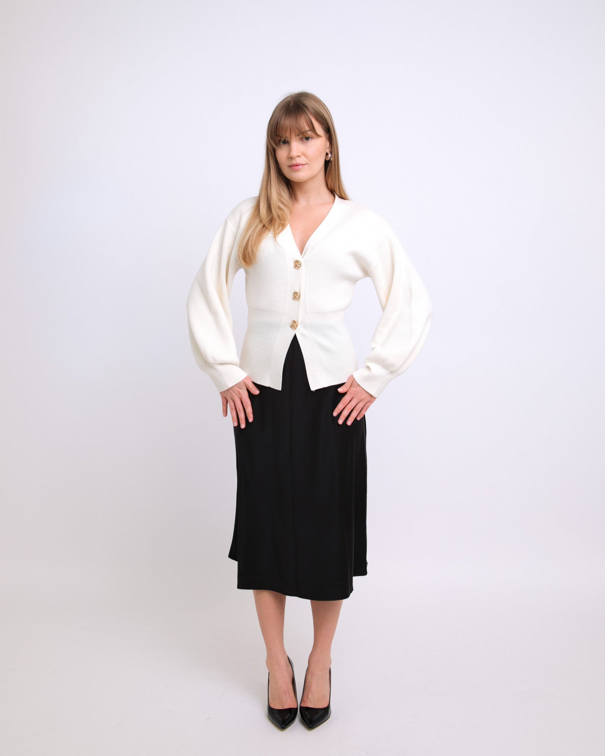 Woman wearing a white cardigan and black skirt on a white background