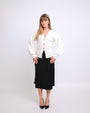 Woman wearing a white cardigan and black skirt on a white background