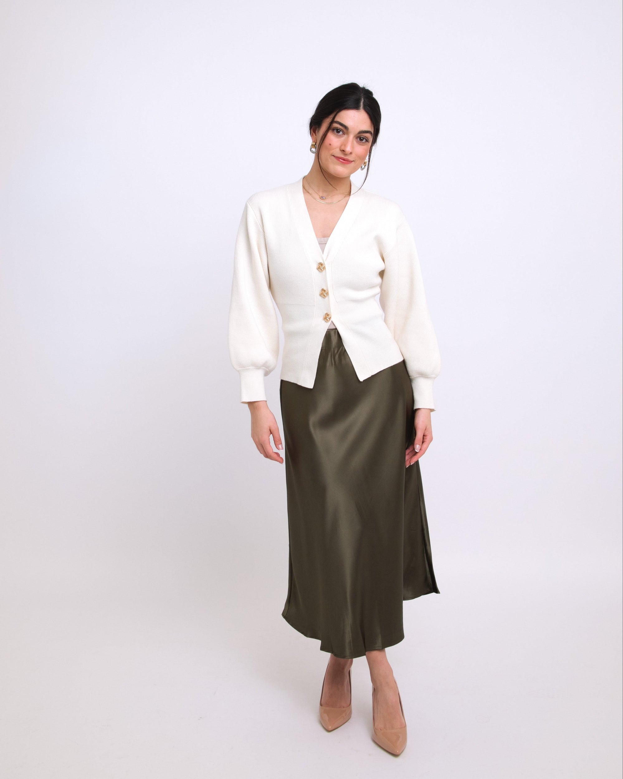 Woman wearing a white cardigan and green skirt on a white background