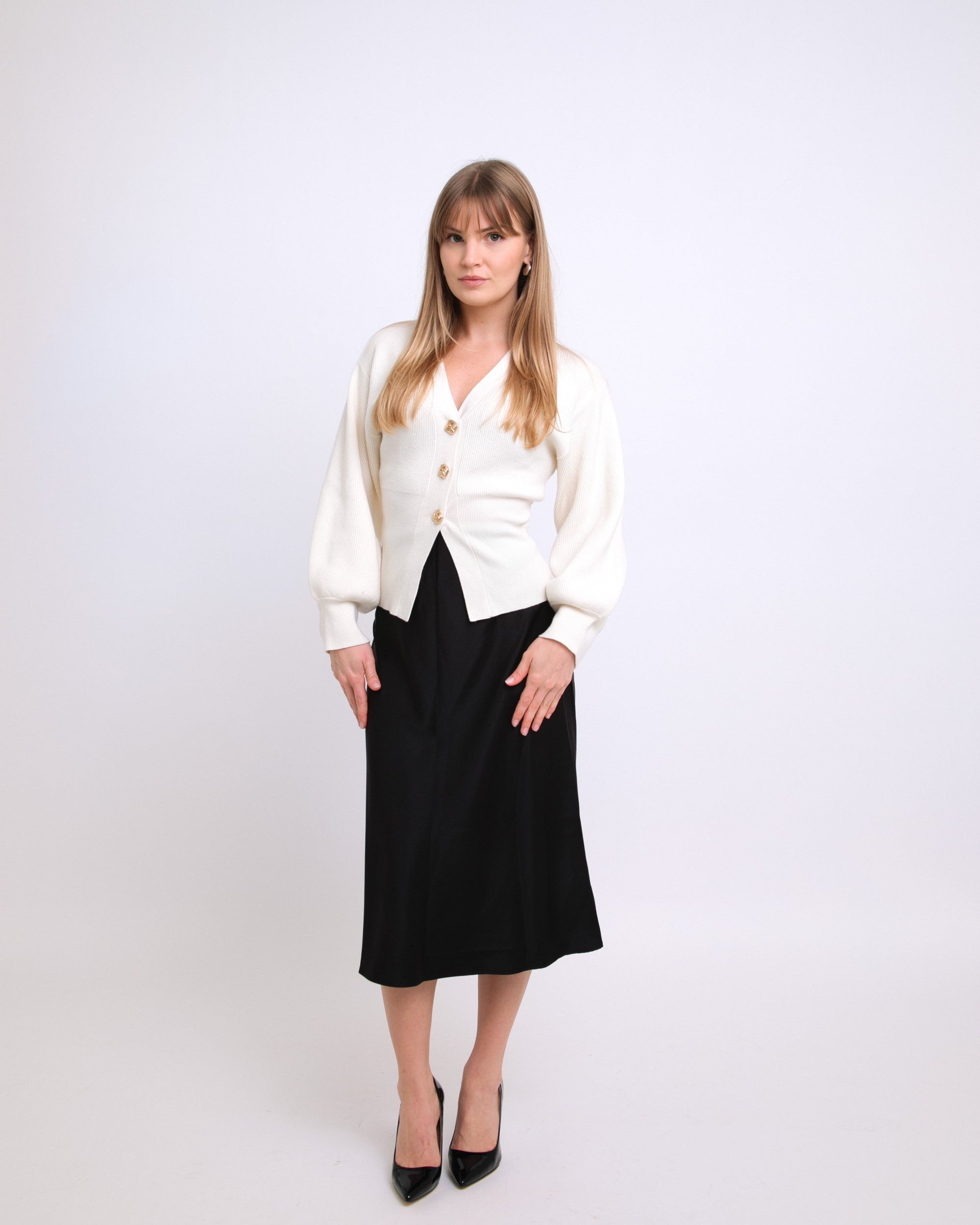 Woman wearing a white cardigan and black skirt on a white background