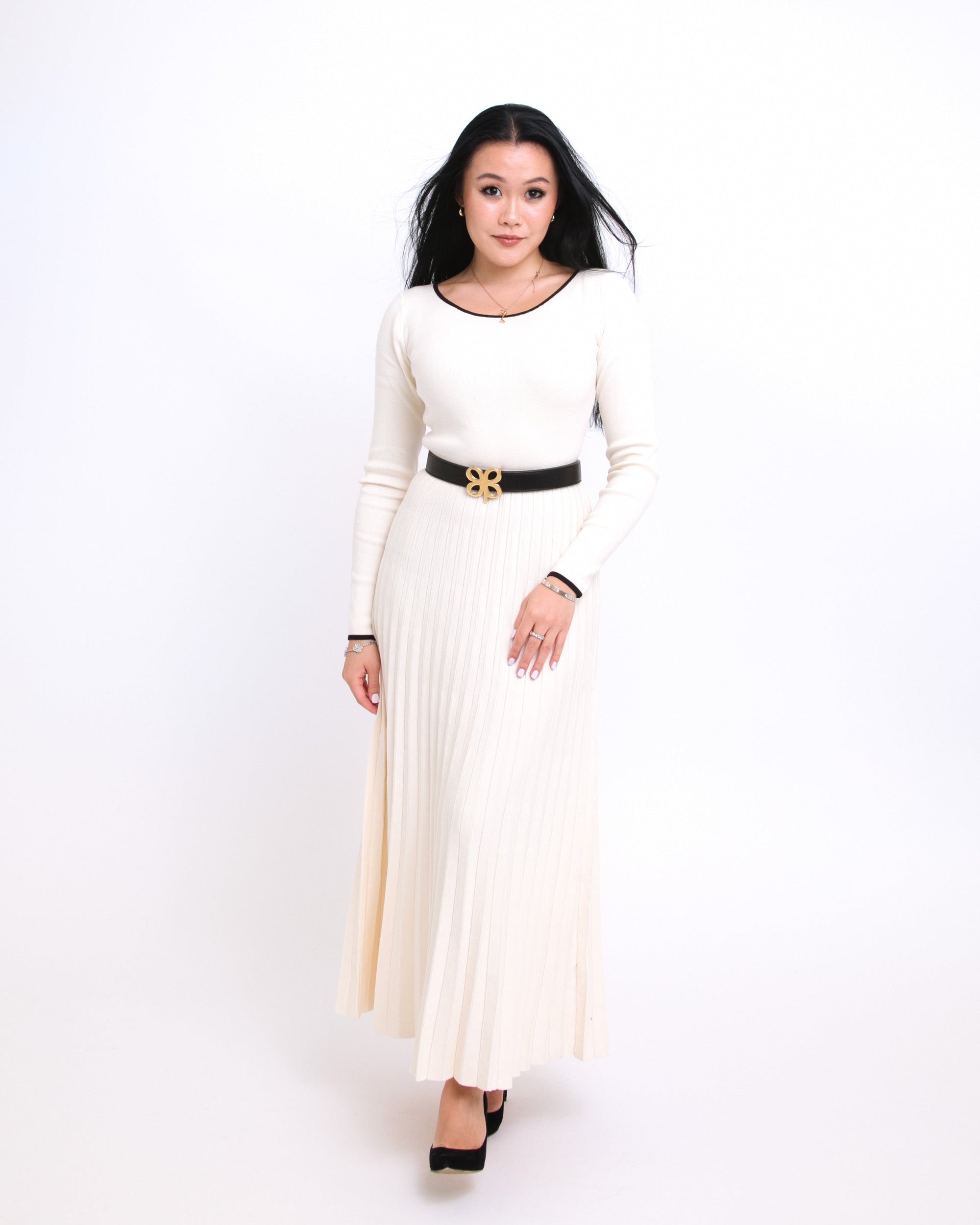 Woman wearing a long white dress with a black belt on a white background