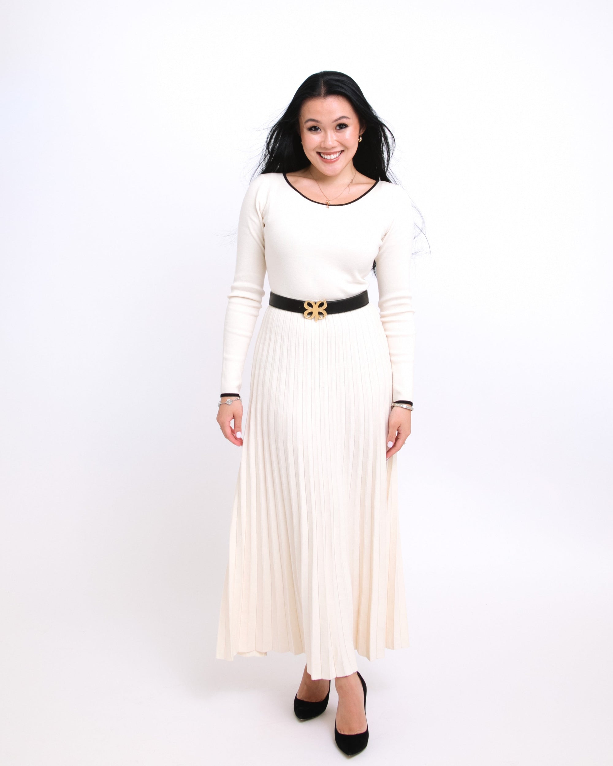 Woman wearing a white dress with a black belt on a white background